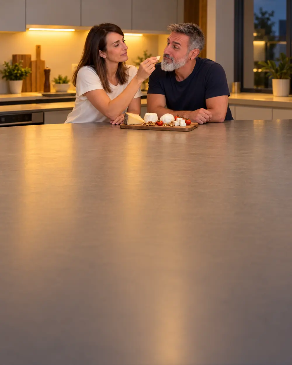 Laura dándole a probar a Jonathan un trozo de queso de una tabla con queso fresco, mozzarella y curado